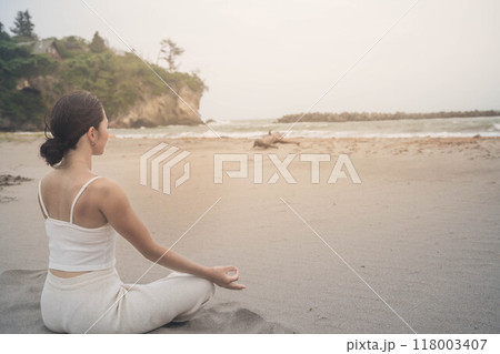 海辺に座ってヨガをしている若い女性 118003407