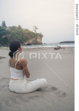 海辺に座ってヨガをしている若い女性 海辺に座ってヨガをしている若い女性 118003408