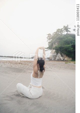 海辺に座ってヨガをしている若い女性 海辺に座ってヨガをしている若い女性 118003411