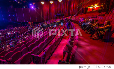 Spectators gather in the auditorium and watch the show in theatre timelapse. Large hall with red armchairs seats Spectators gather in the auditorium and watch the show in theatre timelapse. Large hall with red armchairs seats 118003890