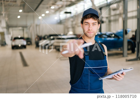 Confident automotive mechanic male pointing finger at camera looking with serious expression., choosing, inviting people,, holding digital tablet, at vehicle repair shop. Concept of auto maintenance. Confident automotive mechanic male pointing finger at camera looking with serious expression., choosing, inviting people,, holding digital tablet, at vehicle repair shop. Concept of auto maintenance. 118005710