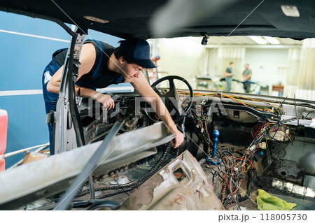 Skilled mechanic male inspecting car for useful things for secondary repairs before recycling in automobile repair and renew service station. Concept of professional car repair and maintenance work. 118005730