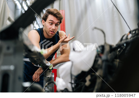 Portrait of puzzled mechanic leaning on car with worried expression on face, unsure of how to fix complex engine problem at vehicle repair shop. Concept of professional car repair and maintenance work Portrait of puzzled mechanic leaning on car with worried expression on face, unsure of how to fix complex engine problem at vehicle repair shop. Concept of professional car repair and maintenance work 118005947