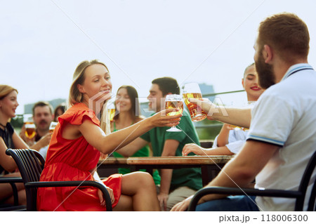 Group of friends sitting at pub terrace talking, drinking alcohol, celebrating meeting after long years. Festive atmosphere. Group of friends sitting at pub terrace talking, drinking alcohol, celebrating meeting after long years. Festive atmosphere. 118006300