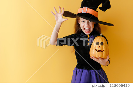 girl in witch costume with Halloween pumpkin girl in witch costume with Halloween pumpkin 118006439