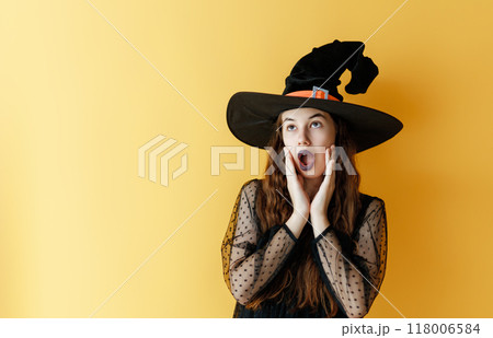 girl in Halloween witch costume on yellow background 118006584