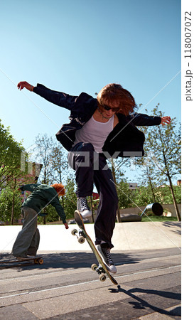Dynamic image of stylish young boys in motion in public park, on sunny day, skateboarding with energy Blending street style and fashion 118007072