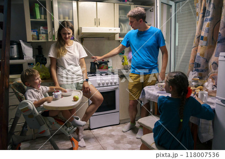 A loving family is happily enjoying quality time together in their cozy kitchen, showcasing warmth and connection 118007536