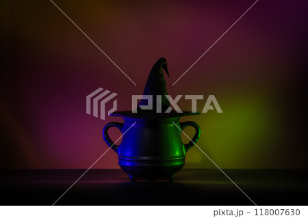 Creative minimalist Halloween background image featuring a witch hat on a cauldron in lowkey neon lighting. Perfect for modern and trendy Halloween designs. Creative minimalist Halloween background image featuring a witch hat on a cauldron in lowkey neon lighting. Perfect for modern and trendy Halloween designs. 118007630