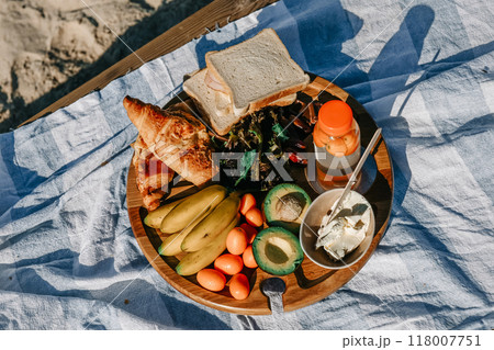A delicious picnic spread featuring fresh fruits, pastries, and drinks on a blanket at the beach A delicious picnic spread featuring fresh fruits, pastries, and drinks on a blanket at the beach 118007751