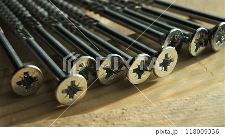 Screws on a wooden board. Close-up of long silver screws. Screws on a wooden board. Close-up of long silver screws. 118009336
