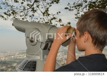 boy observing city panorama through stationary binoculars. Traveling with a child concept boy observing city panorama through stationary binoculars. Traveling with a child concept 118009614