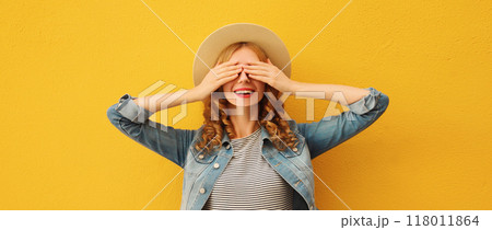 Stylish surprised young woman covering her eyes with hands in summer straw hat on orange background 118011864