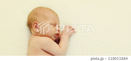 Portrait of sweet baby, infant sleeping lying on white bed at home 118011884