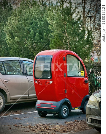 Red Retro Styled Small Mobility Scooter Vehicle In Parking Space Red Retro Styled Small Mobility Scooter Vehicle In Parking Space 118012121