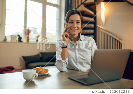Dark-haired pretty woman sitting at the laptop and having a video call Dark-haired pretty woman sitting at the laptop and having a video call 118012238