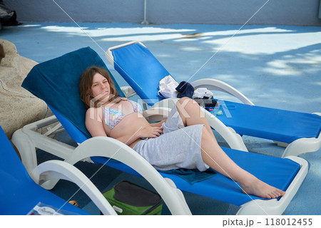 Relaxing Summer Vacation: Teenage Girl Lounging on Sunbed in Mediterranean Paradise with Palm Trees and Blue Sky. Idyllic Mediterranean Getaway: Young Girl Sunbathing on Sunbed Amidst Palm Trees Relaxing Summer Vacation: Teenage Girl Lounging on Sunbed in Mediterranean Paradise with Palm Trees and Blue Sky. Idyllic Mediterranean Getaway: Young Girl Sunbathing on Sunbed Amidst Palm Trees 118012455