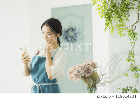 スマホを見るエプロンの女性　 118014231