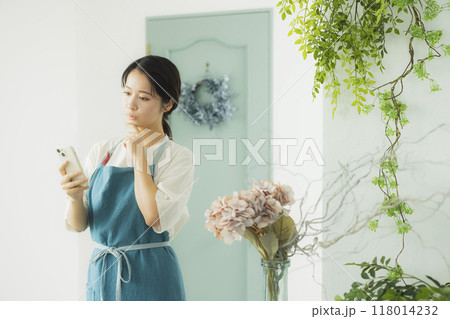スマホを見るエプロンの女性　 118014232