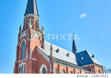 Majestic Red Brick Church with Gothic Spires Against Blue Sky 118017031