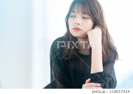 リビングの窓際でスキンケアをする若い女性 118017424