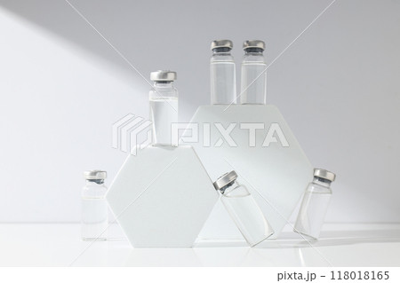Glass medical bottles with vaccine and decorative blocks on white background 118018165