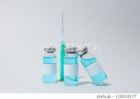 Glass medical bottles with vaccine and syringe on light background Glass medical bottles with vaccine and syringe on light background 118018177