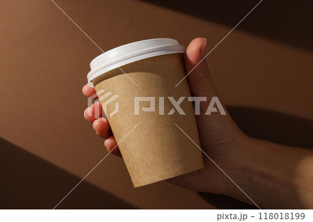 Paper cup with a lid on a brown background 118018199