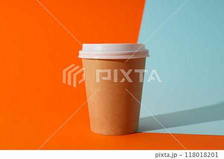 A paper cup with a lid on an orange background 118018201