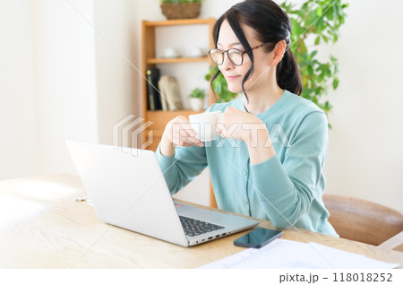 コーヒーを片手にパソコンで仕事をするミドル女性 コーヒーを片手にパソコンで仕事をするミドル女性 118018252