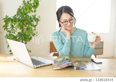 テーブルでパンフレットを見るミドル女性 118018314