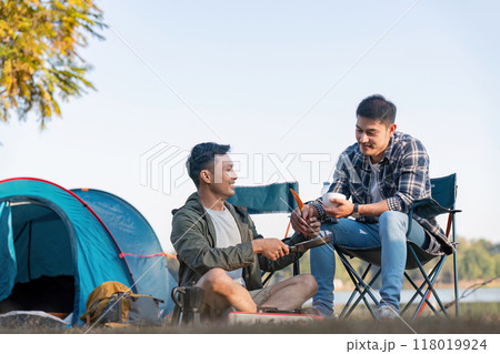 Gay couple cooking together while camping outdoors Gay couple cooking together while camping outdoors 118019924