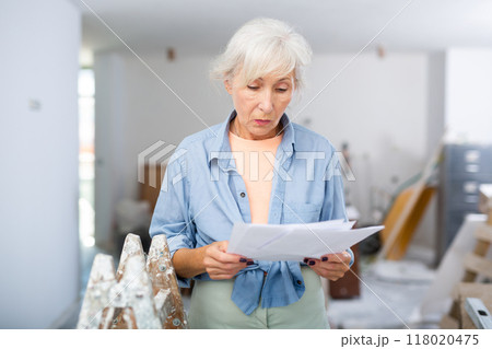 Stressed woman with papers in renovating house 118020475