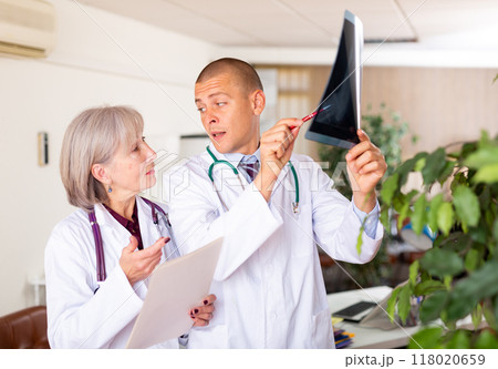 Two doctors examining x-ray of patient and discussing diagnosis 118020659
