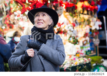 Smiling aged woman walking at traditional city christmas fair 118020824