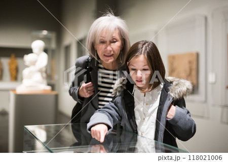 Senior woman and tween girl observing arts and crafts in museum 118021006