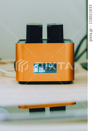 オレンジ色のバッテリーチャージャーで充電中のバッテリー オレンジ色のバッテリーチャージャーで充電中のバッテリー 118021635