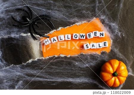 curl of torn black paper on orange background. halloween sale concept 118022009