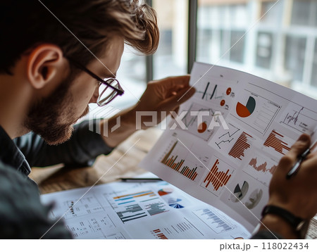 Entrepreneur reviewing a detailed business plan with graphs and charts, business strategy visualizat Entrepreneur reviewing a detailed business plan with graphs and charts, business strategy visualizat 118022434