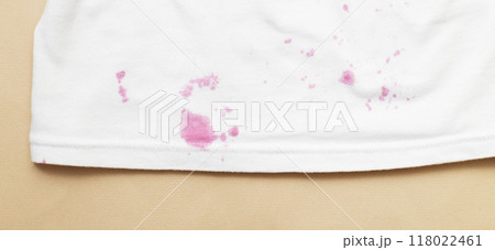 dirty stains on a white T-shirt from berries and drink on beige background 118022461