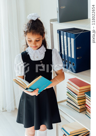 Schoolgirl reading a book in the library 118022654