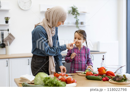 Muslim mother and daughter preparing salad ingredients together in kitchen 118022798