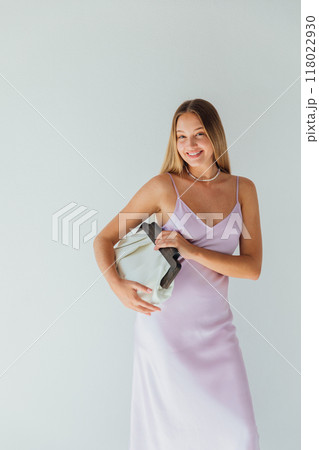Beautiful fashionable blonde woman in silk dress holding clutch and smiling Beautiful fashionable blonde woman in silk dress holding clutch and smiling 118022930