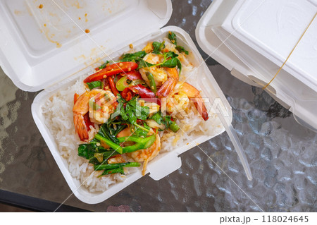 Popular stir-fried basil shrimp served over hot rice in an eco-friendly paper box, a delicious made-to-order meal on the dining table Popular stir-fried basil shrimp served over hot rice in an eco-friendly paper box, a delicious made-to-order meal on the dining table 118024645