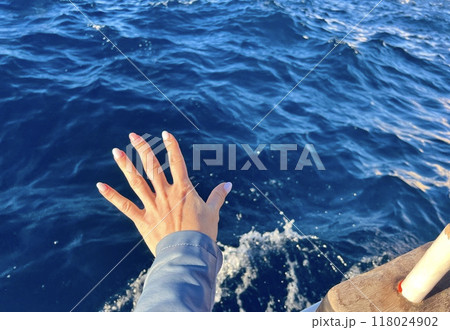 Human hand with the view of the sea from the boat on the background of the waves. 118024902