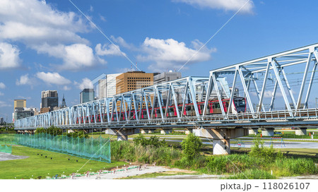 多摩川を渡る電車と川崎駅前のビル群の風景【神奈川県・川崎市－東京都・大田区】 118026107