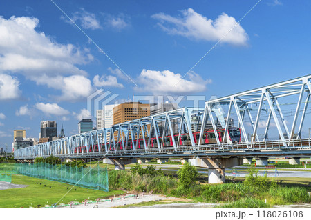 多摩川を渡る電車と川崎駅前のビル群の風景【神奈川県・川崎市－東京都・大田区】 118026108