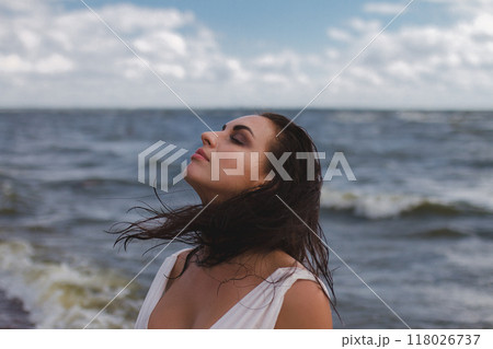 banner, portrait of brunette woman in profile looks to right with wet flying hair against background of sea 118026737