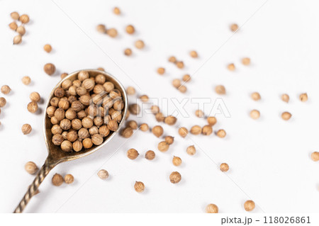 Coriander Grains in a Spoon on a White Background. Coriander Grains in a Spoon on a White Background. 118026861