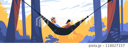 Man relaxing in hammock between trees reading book in forest with vibrant foliage and clear sky 118027157
